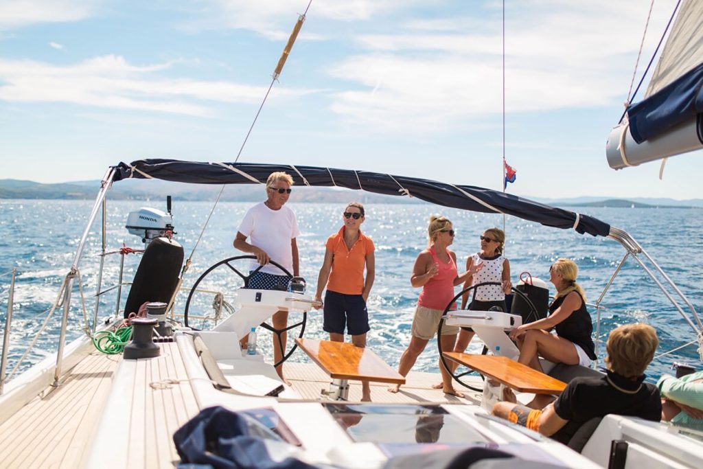  A group of older adult friends at the twin helm stations of a sailing yacht